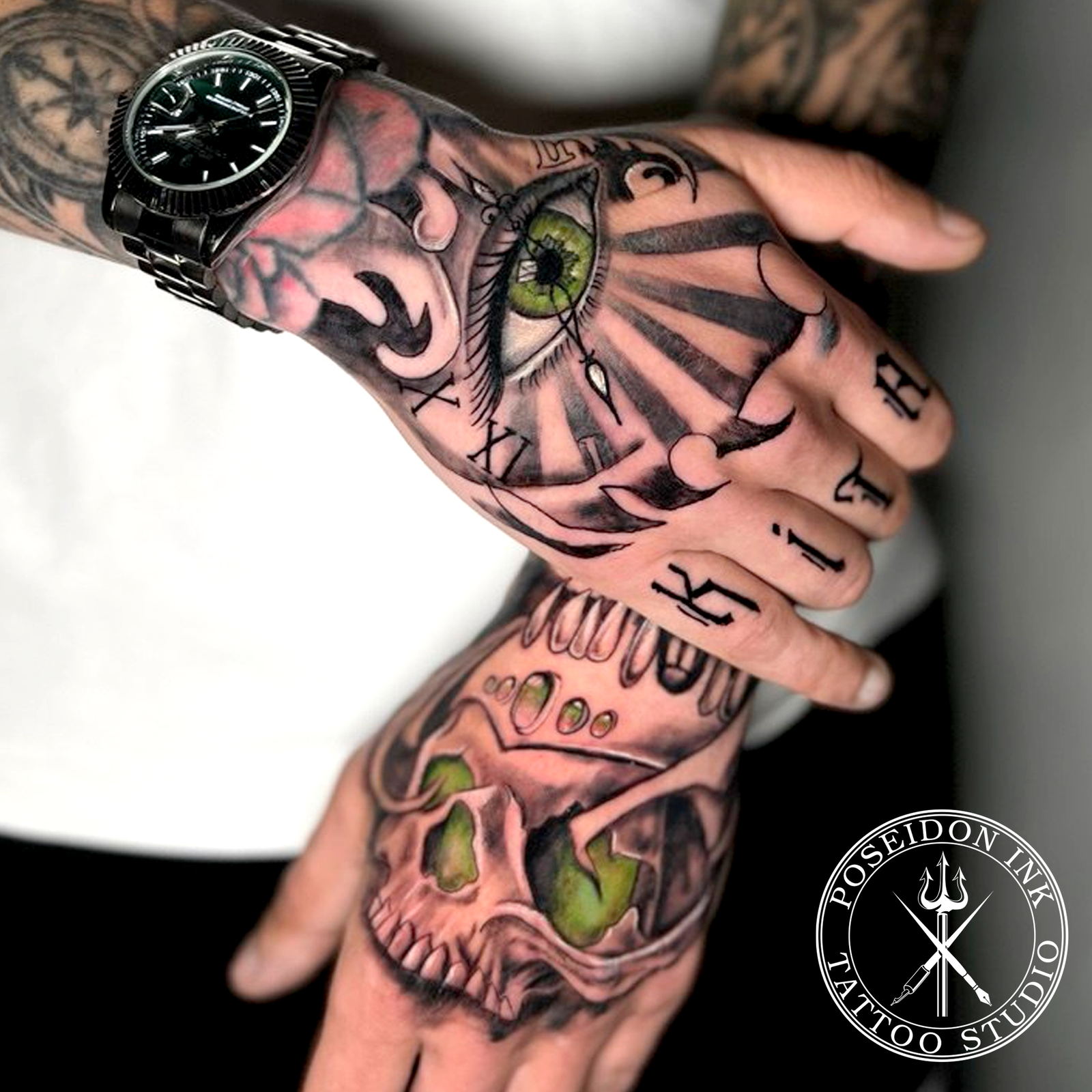 Hand tattoos of an all-seeing eye over Roman clock numerals and a crowned skull, with gothic knuckle lettering