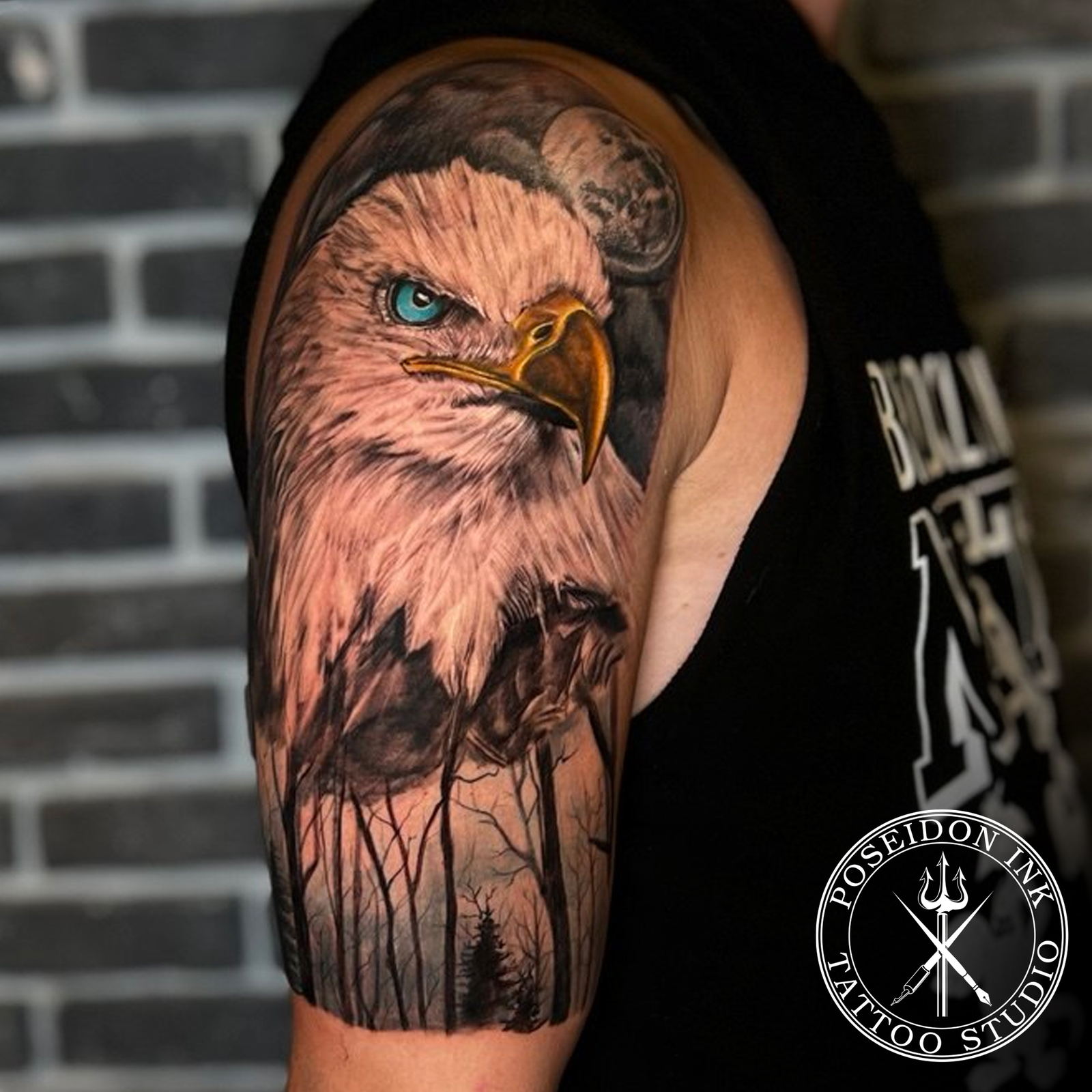 Realistic bald eagle tattoo with turquoise eye and yellow beak, full moon and misty forest on the upper arm