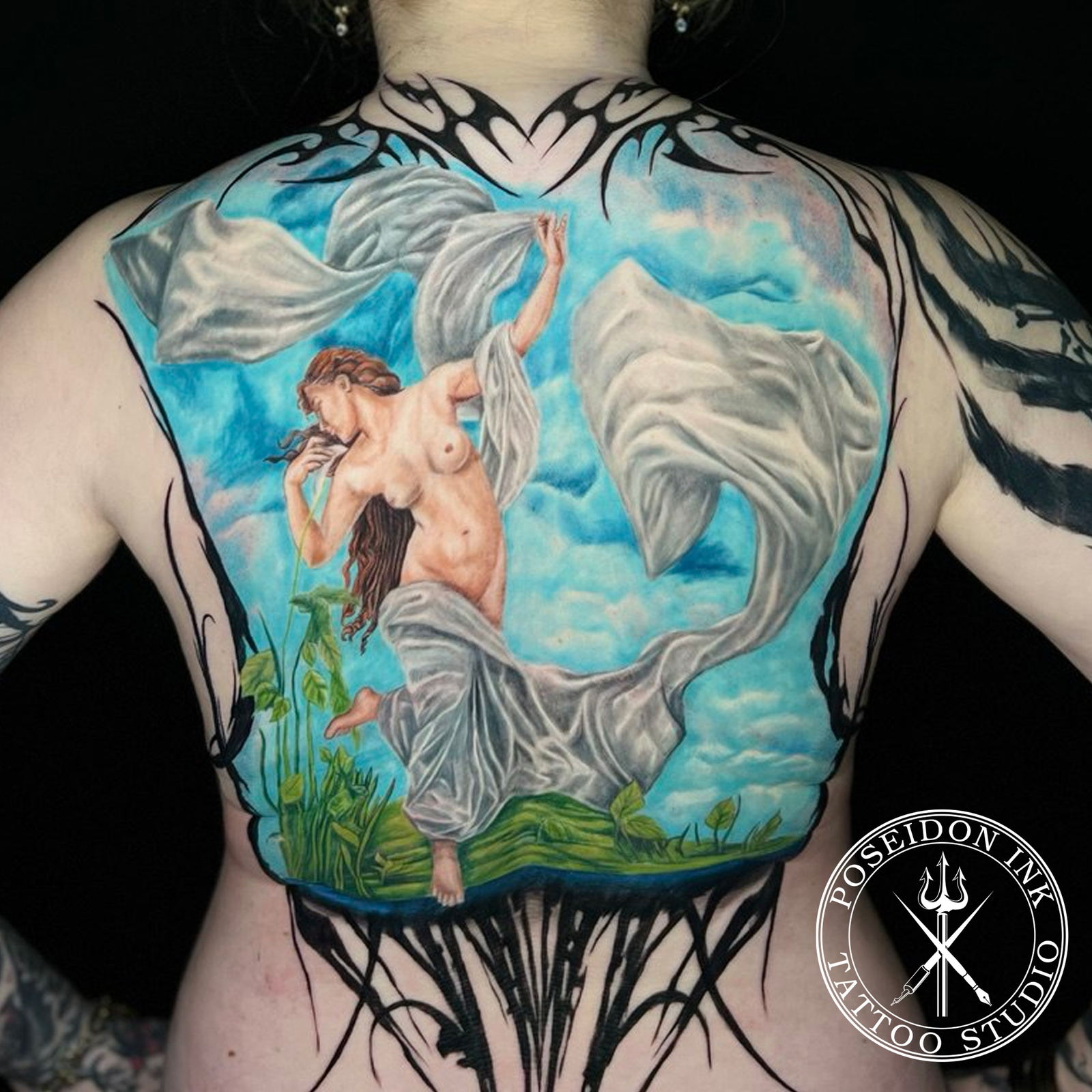 Full back colour realism tattoo of a classical figure with white drapery against a blue cloudy sky
