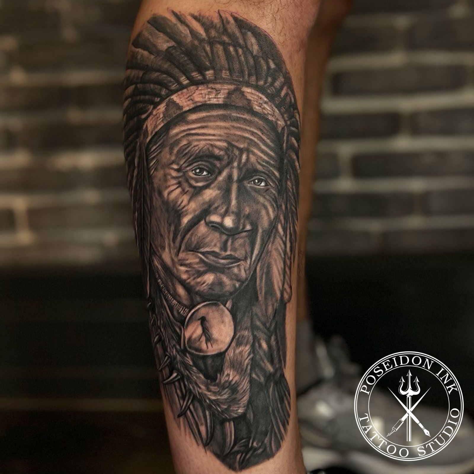 Photorealistic black and grey tattoo portrait of a Native American chief in a feathered war bonnet on the calf