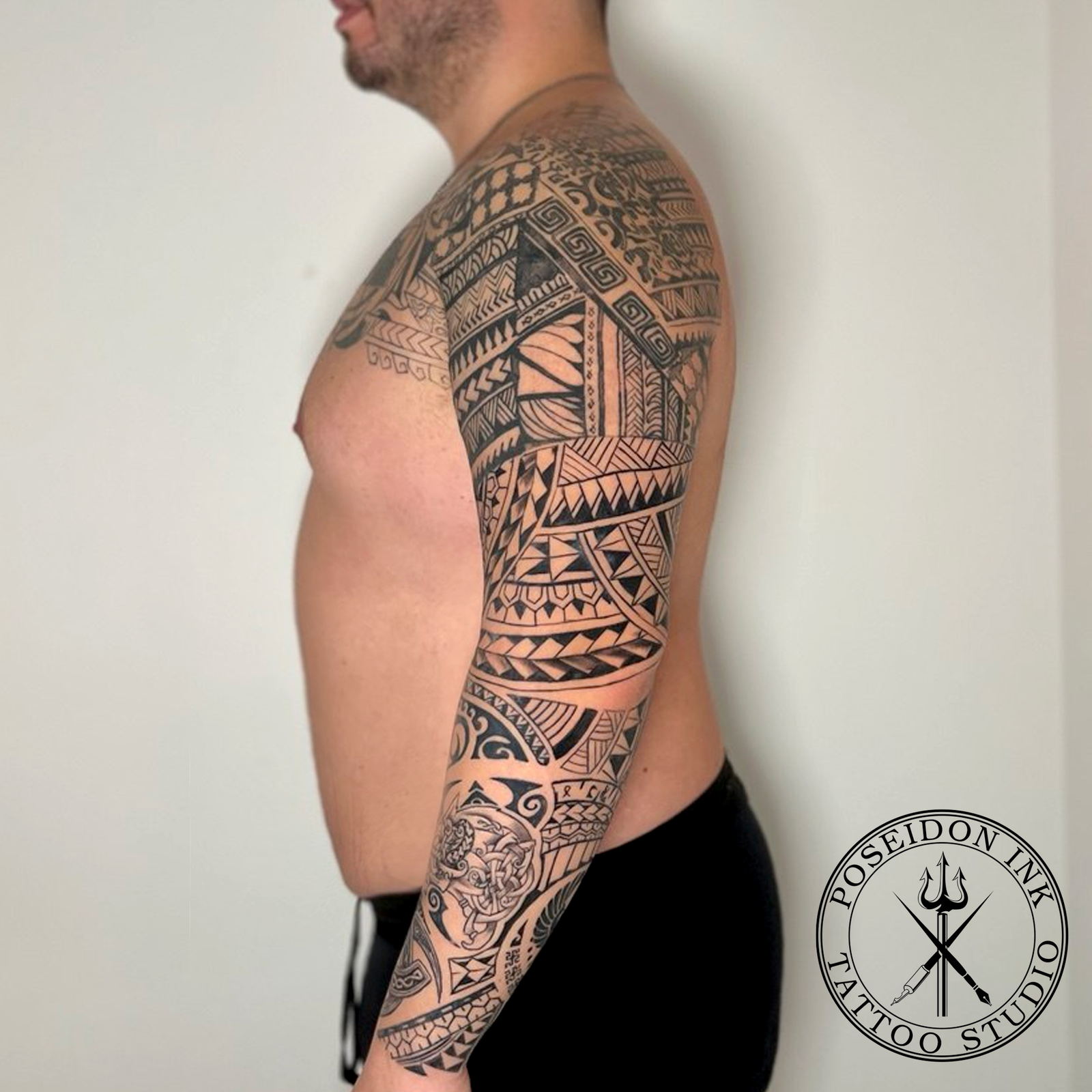Polynesian tribal tattoo sleeve with spearhead, weave and shark tooth patterns extending across the chest, in solid blackwork