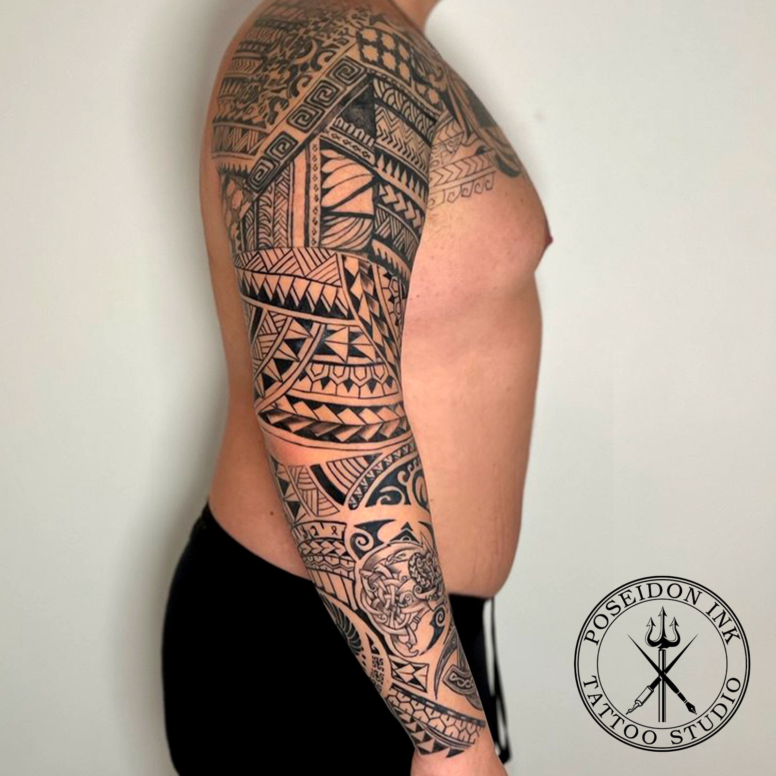 Polynesian tribal full sleeve tattoo with Norse knotwork medallion, bold blackwork bands from shoulder to wrist