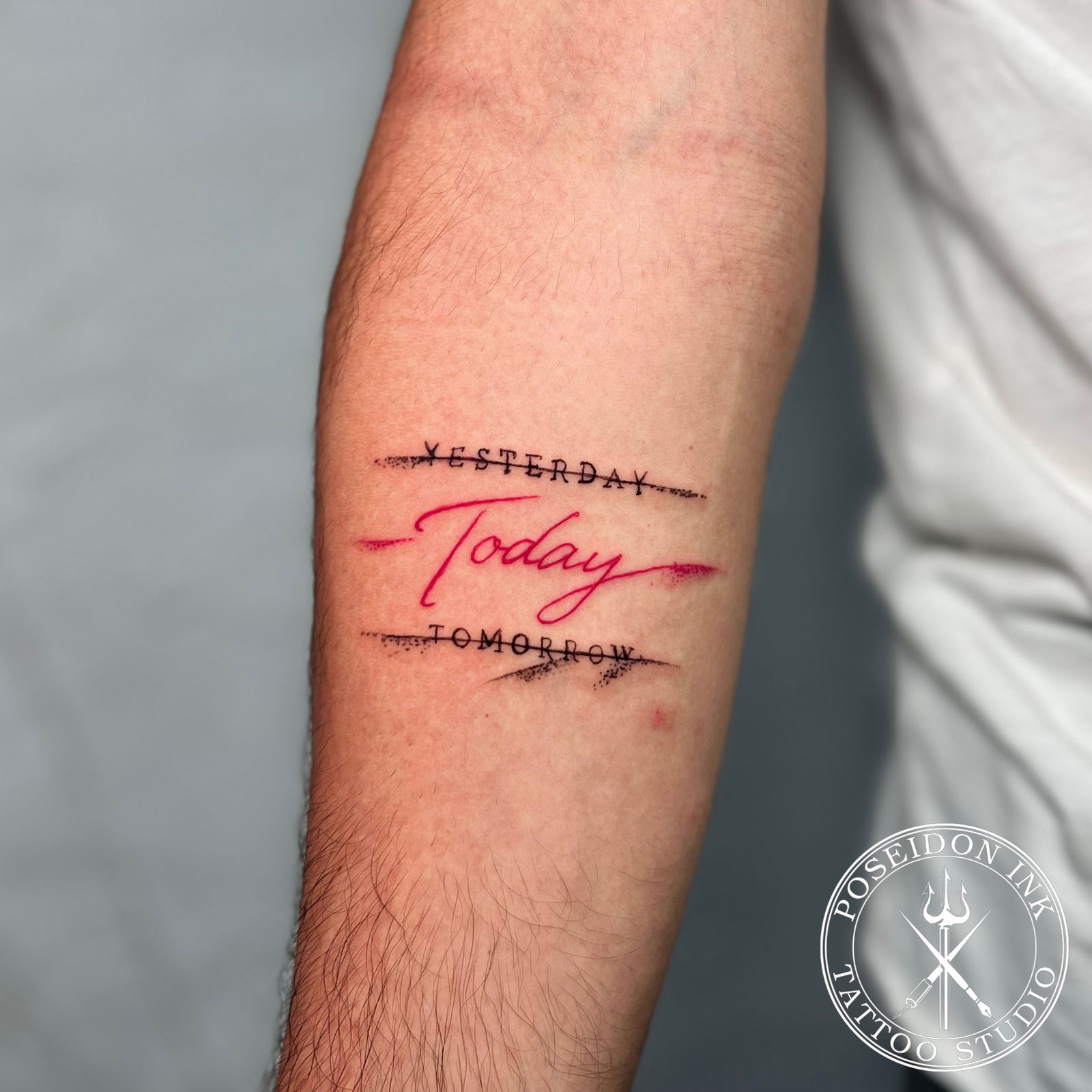 Lettering tattoo with the words Yesterday and Tomorrow crossed out and Today written large in red cursive, inner forearm